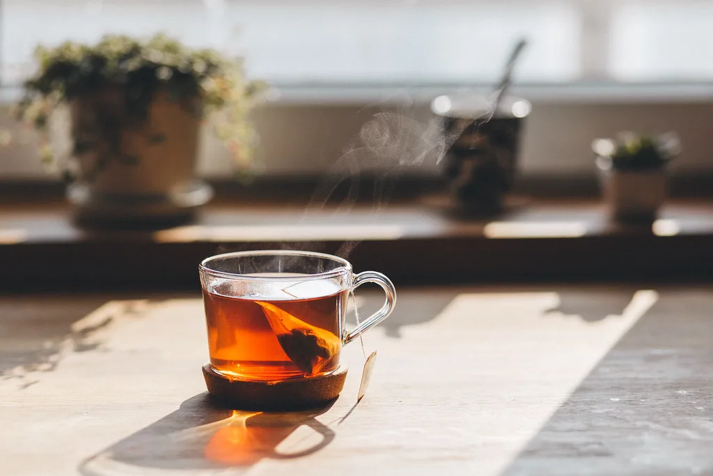 Steaming cup of tea with a tea bag on a kitchen counter