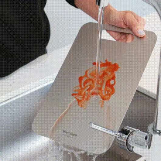 Tomato sauce rinsing off a Vanotium titanium cutting board under the tap
